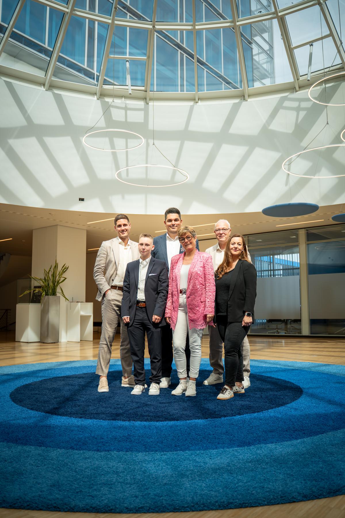 Teamfoto in einer modernen Empfangshalle mit Glaskuppel – Zusammenarbeit mit Volksbank Immobilien Kassel Göttingen