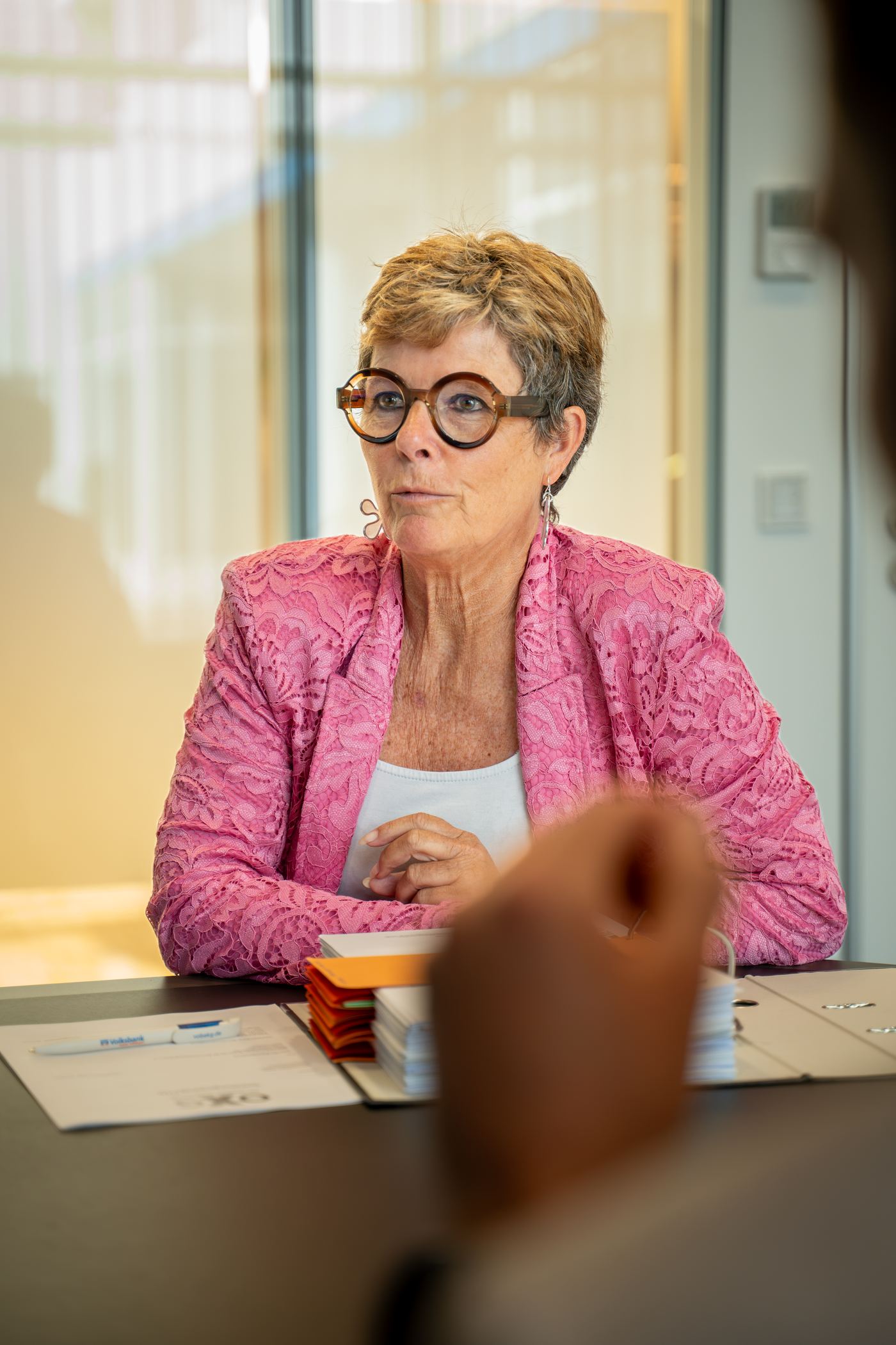Person im Beratungsgespräch mit Unterlagen und Ordnern auf dem Tisch – persönliche Betreuung im Rahmen der SEV-Verwaltung von Volksbank Immobilien Kassel Göttingen