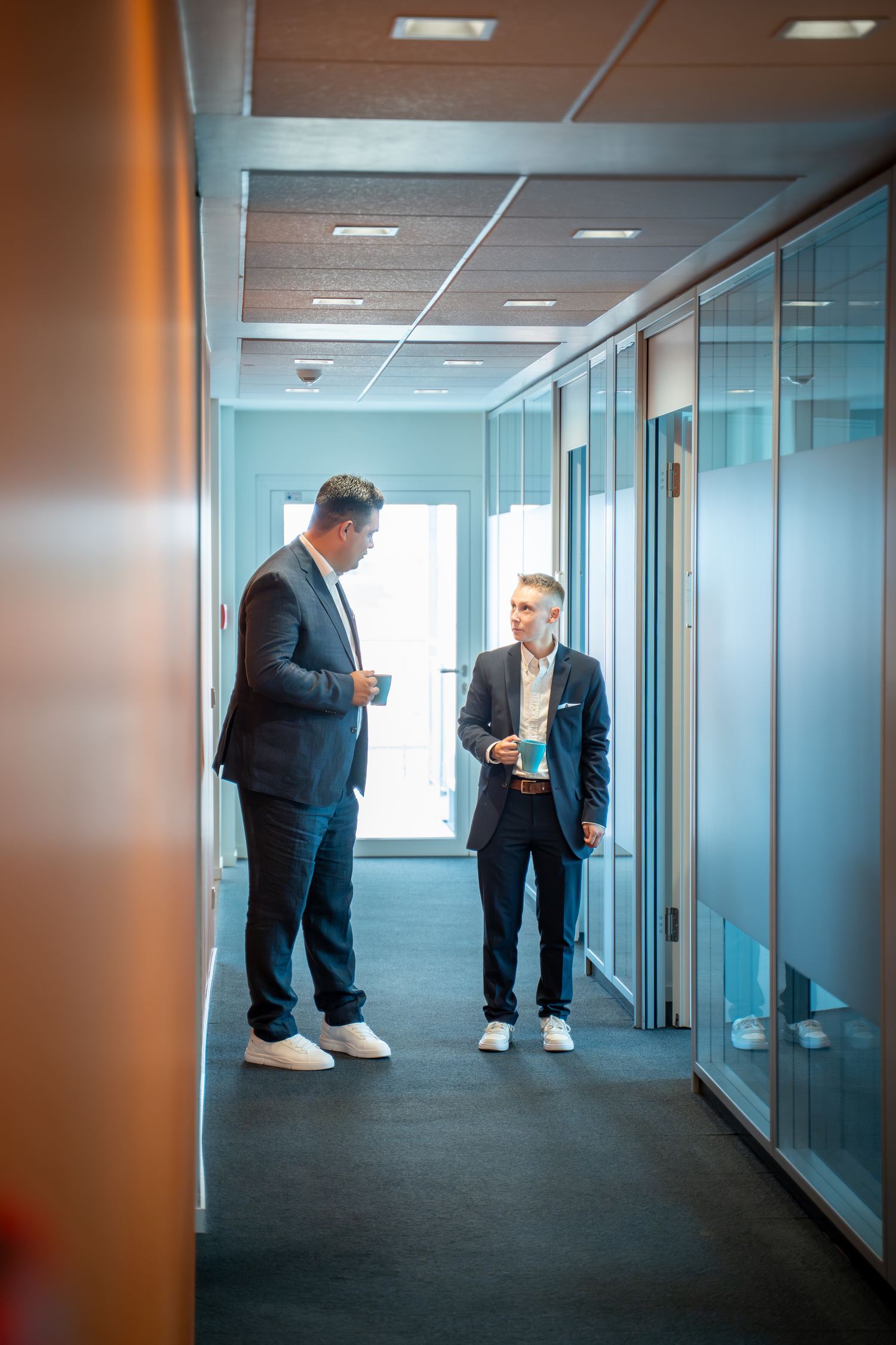 Kurzer Austausch zwischen Kollegen im modernen Büroflur – Team der Mietverwaltung von Voba Immobilien Kassel Göttingen