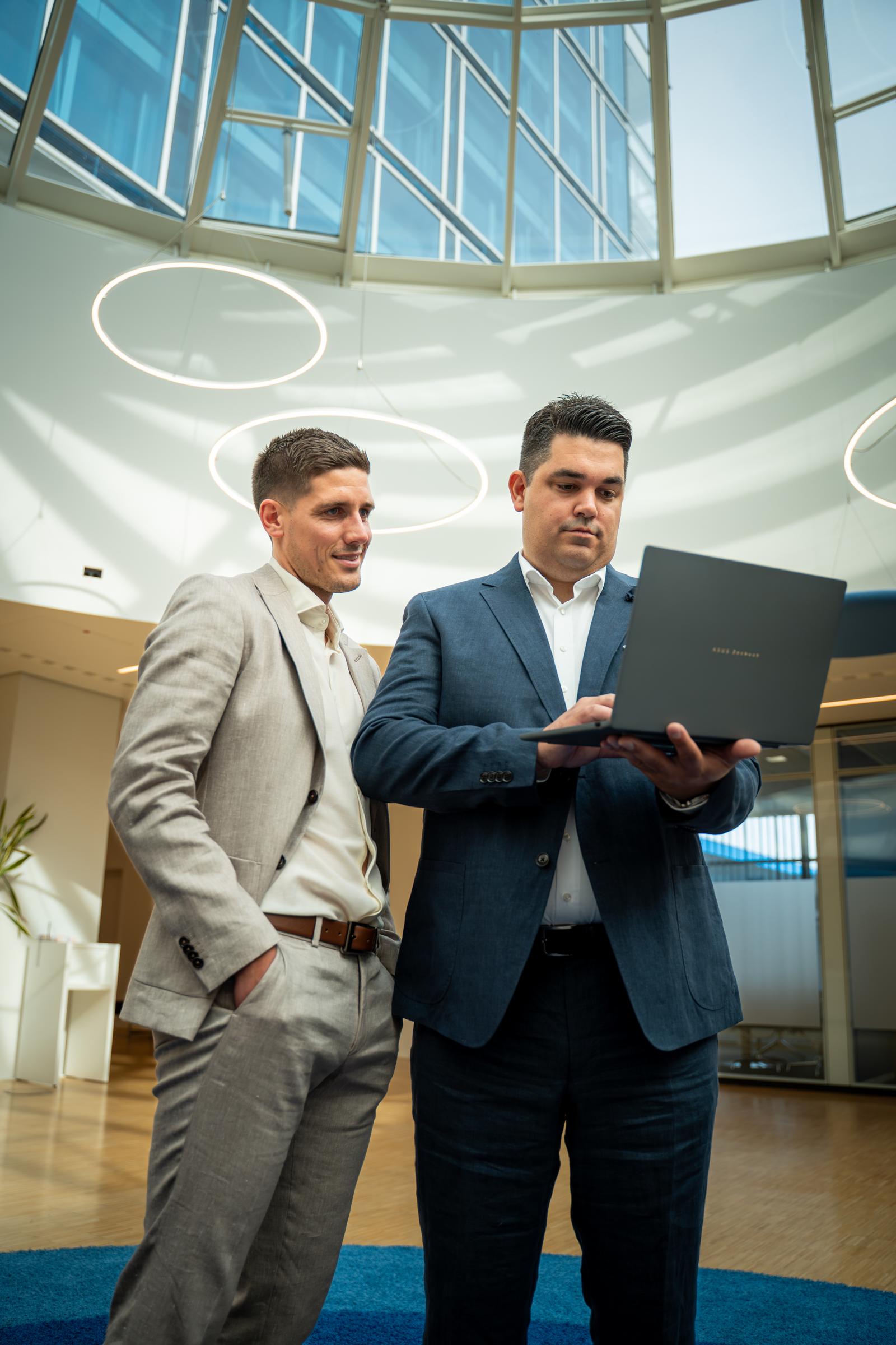 Austausch von zwei Mitarbeitern über die gemeinsamen Fachpartner der Volksbank Immobilien GmbH Kassel Göttingen mit Blick auf einen Laptop 