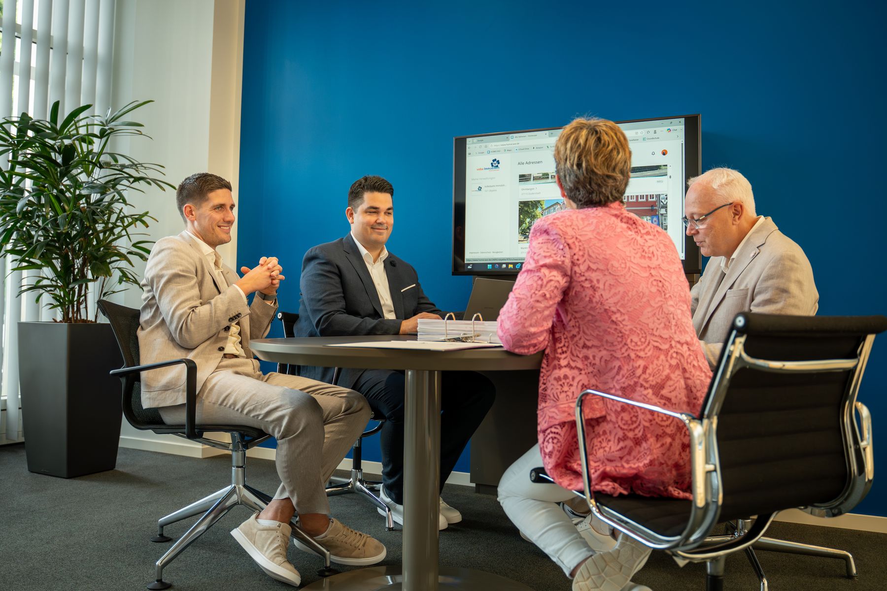 Teambesprechung am runden Tisch mit Blick auf Objektübersicht am Bildschirm – professionelles Property Management von Volksbank Immobilien Kassel Göttingen