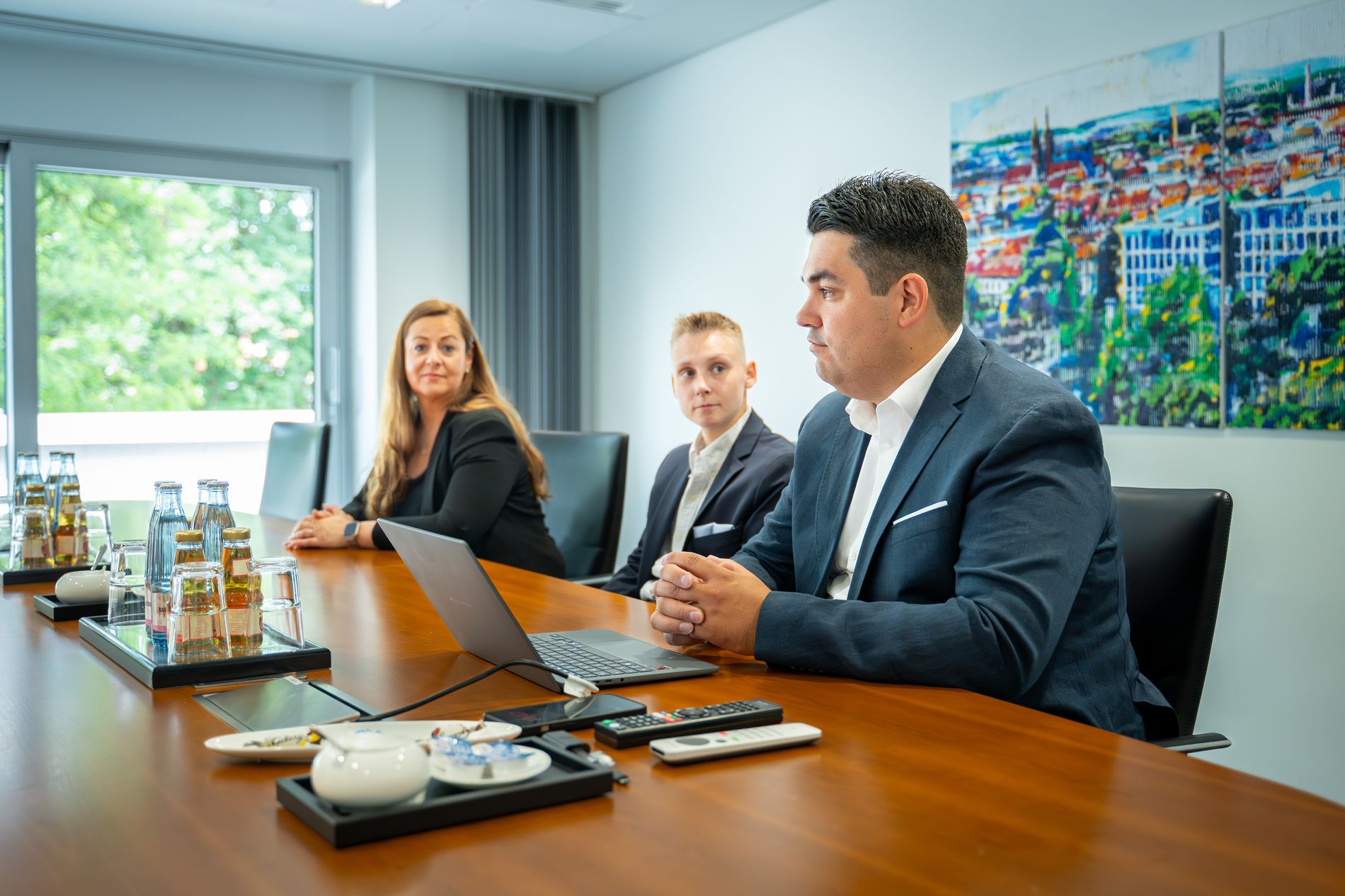 Drei Mitarbeitende im Konferenzraum bei einer Besprechung mit Laptop – enge Zusammenarbeit mit Volksbank Immobilien Kassel Göttingen