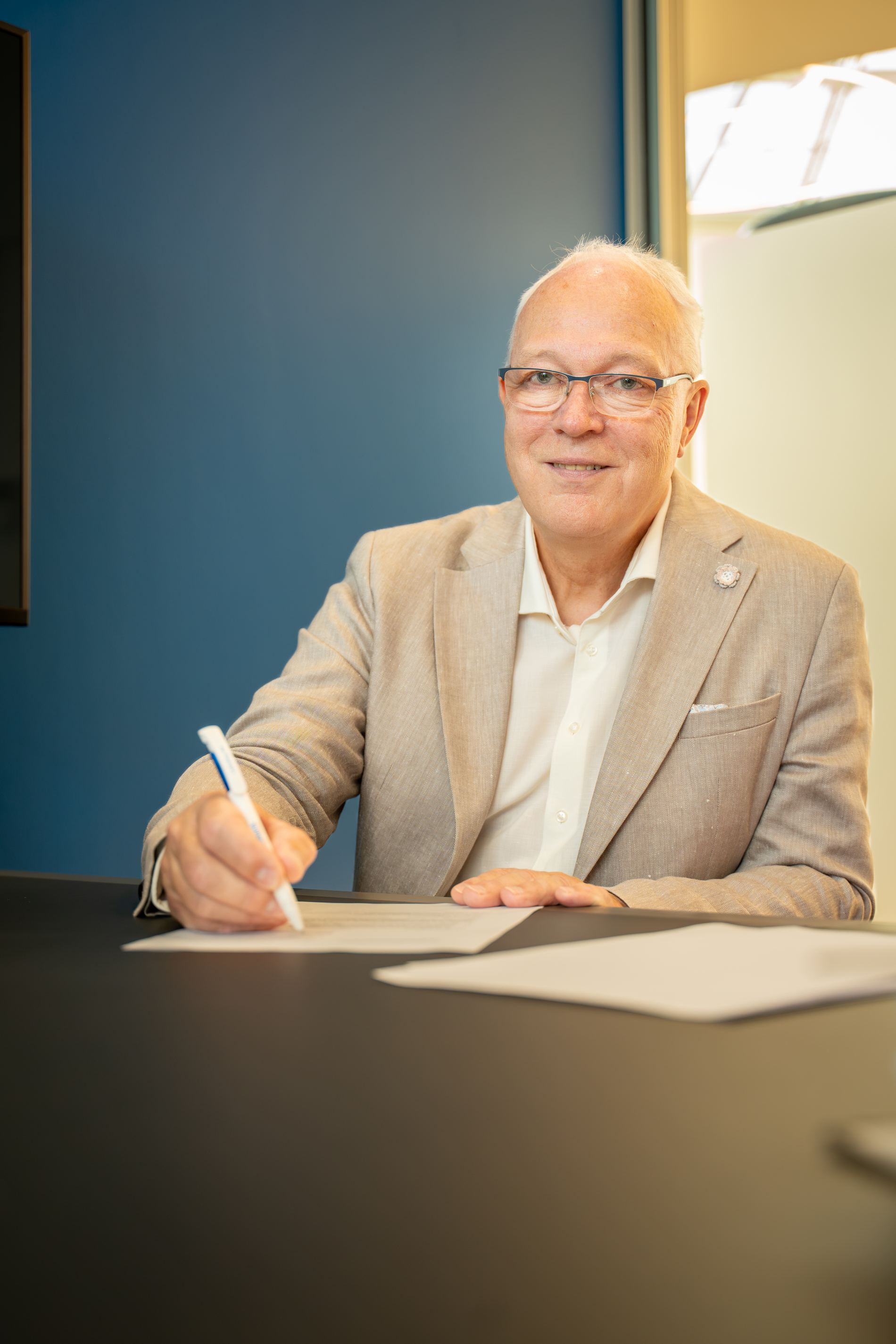 Lächelnder Mitarbeiter unterschreibt ein Dokument für eine Zusammenarbeit innerhalb der professionellen Mietverwaltung