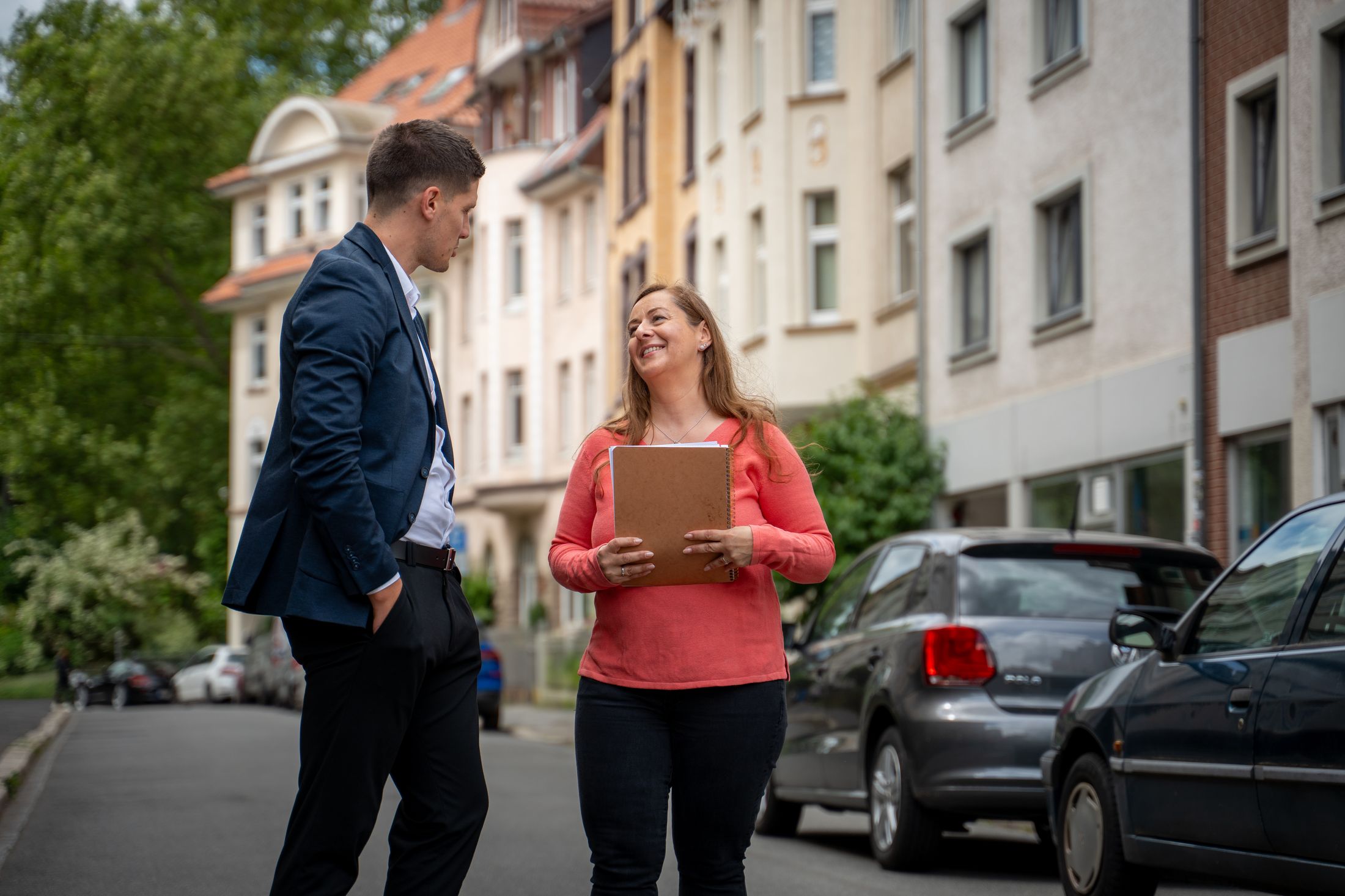 Zwei Mitarbeiter im Gespräch auf der Straße vor Altbauten – Austausch im Rahmen der WEG-Verwaltung von Voba Immobilien Kassel Göttingen